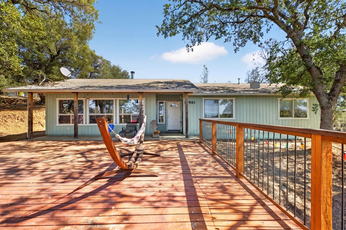 Wide wraparound deck under oak trees at a Creek Trail home in Redding